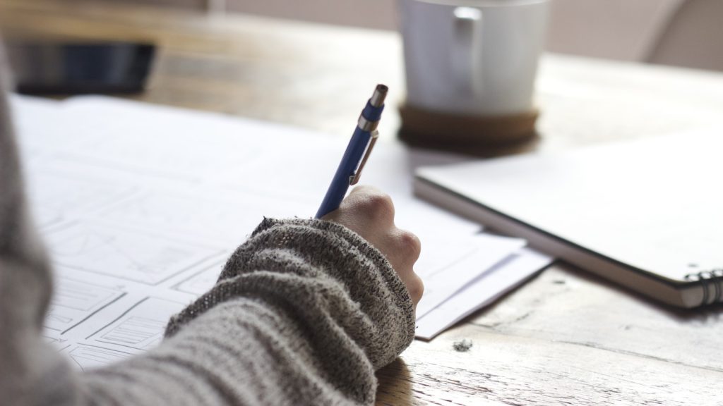 Hand die een administratief formulier invult / Une main remplit un formulaire administratif
